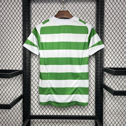 Green and white striped Celtic 05/06 home shirt on a hanger against a black metal grid background