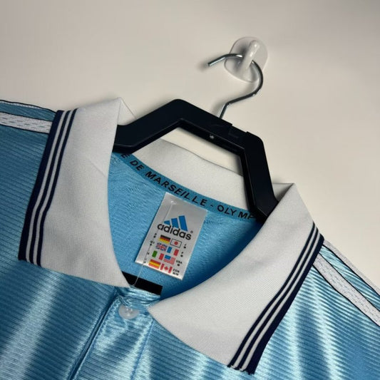 Blue and white Marseille 98/99 away shirt  with Adidas logo on a hanger