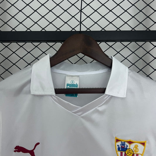 White Sevilla 87-90 home shirt with Puma logo on a hanger against a tiled wall.