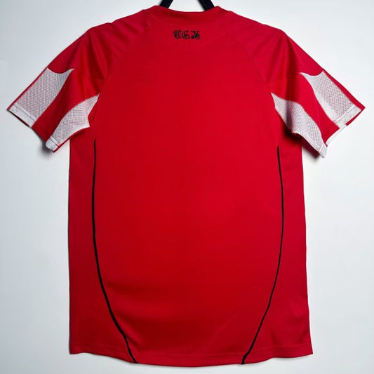 Red Bayern Munich 10/11 home shirt with white accents on a hanger against a light gray background