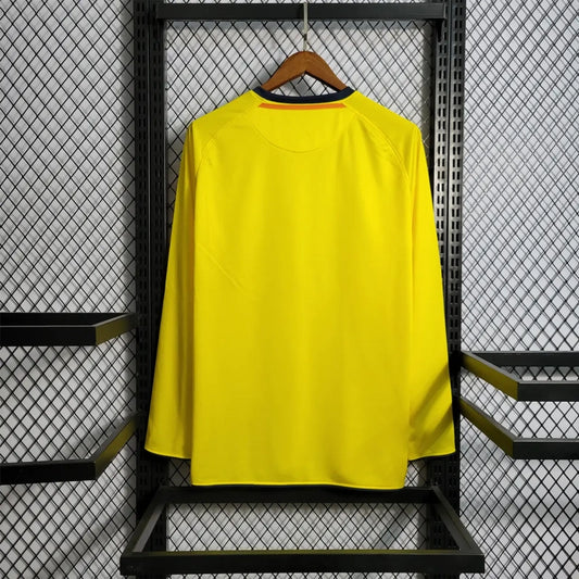 Yellow Barcelona 08/09 long sleeve away shirt on a hanger against a black metal grid background