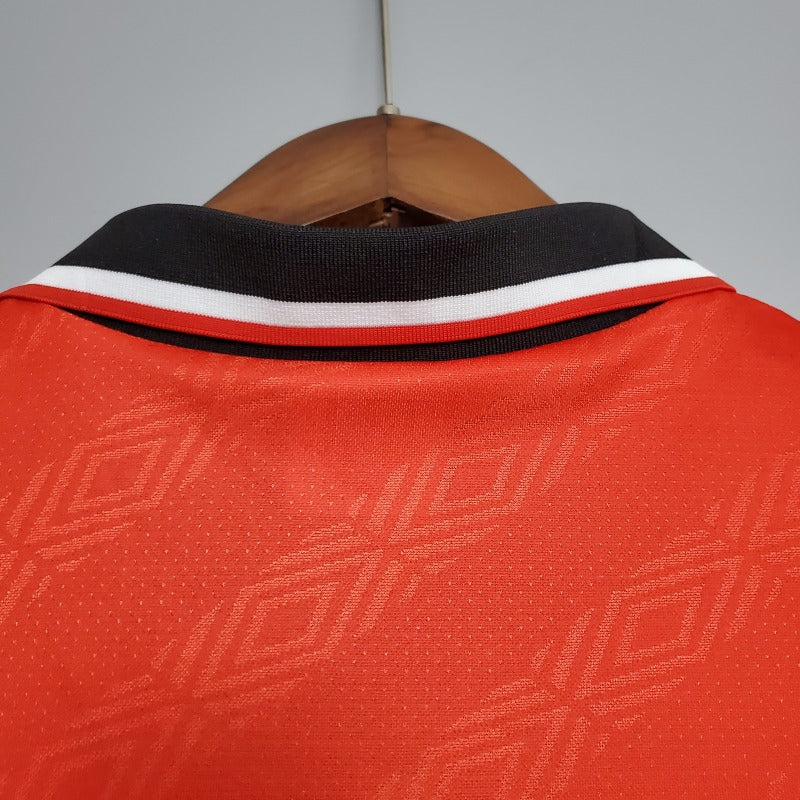 Red Nottingham forest 95/96 home shirt with black and white collar on a wooden hanger against a gray background