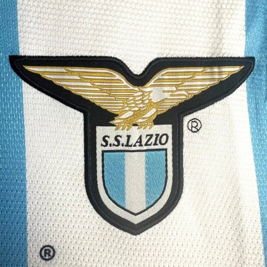 S.S. Lazio logo on a sports jersey with blue and white stripes.