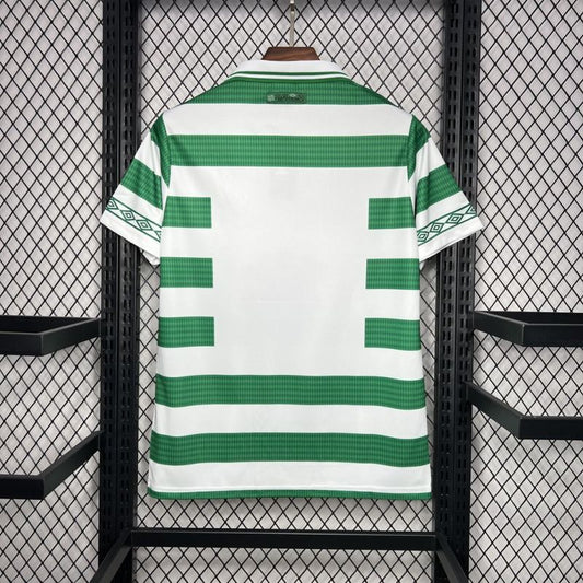 Green and white striped Celtic 98/99 home shirt on a hanger against a black metal grid background
