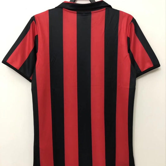 Red and black striped Ac Milan 88/89 home shirt on a hanger against a white background
