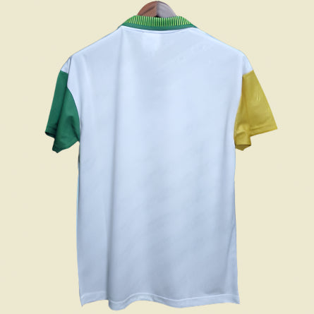 White 93-95 Celtic away shirt  with green and yellow sleeves on a hanger against a black background