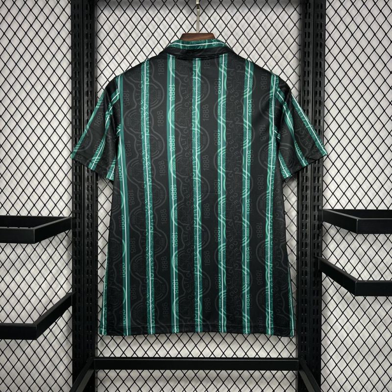 Green and black striped Celtic 92/93 away shirt on a hanger against a grid-patterned wall.