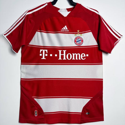 Red Bayern Munich 07/08 home shirt with white accents on a hanger against a light gray background
