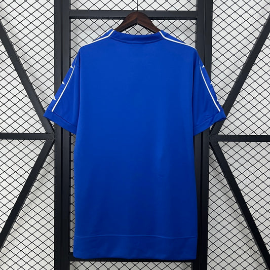 Blue Juventus 99/00 away shirt  hanging against a black metal grid background