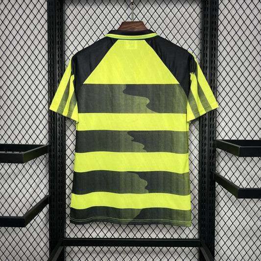 Black and yellow striped Celtic 96/97 away kit on a hanger against a wire mesh background