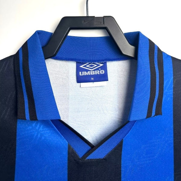 Blue and black Inter Milan 95/96 home shirt with Umbro logo on a hanger against a white background
