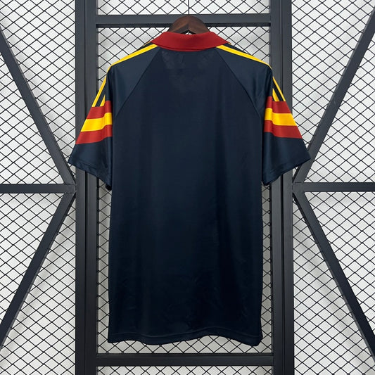 Roma 91/92 third shirt shirt with red and yellow stripes on a hanger against a geometric patterned background