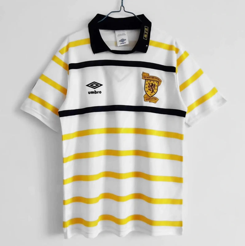 White Scotland 1988 away shirt with yellow stripes and Umbro logo on a gray background