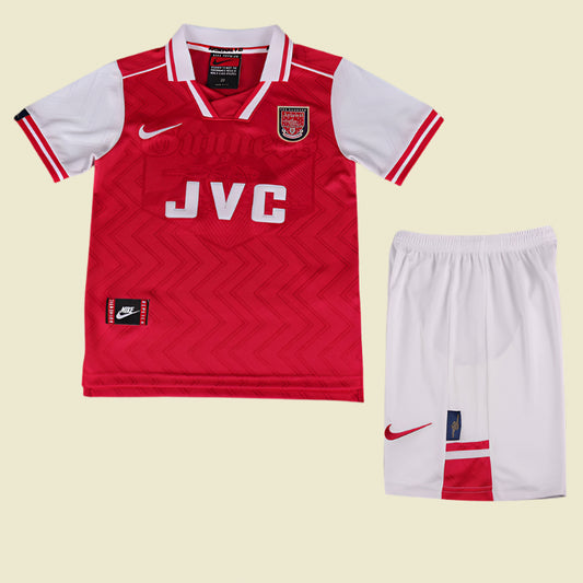 Red Arsenal 96/97 home kids kit with white accents and matching shorts on a textured gray background