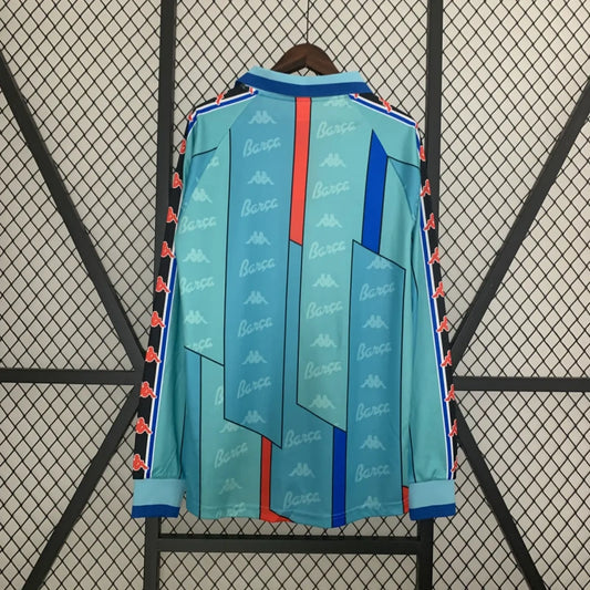 Light blue Barcelona 96/97 long sleeve away shirt with red and blue accents on a hanger against a black wire mesh background