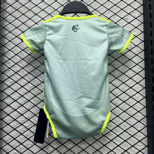 Light green Mexico 2024 away baby onesie with yellow accents on a hanger against a checkered floor background