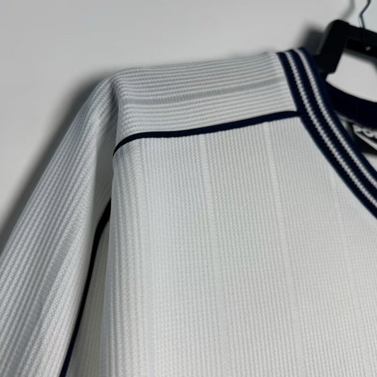 White Tottenham 97-99 long sleeve home shirt with black trim on a hanger against a light gray background