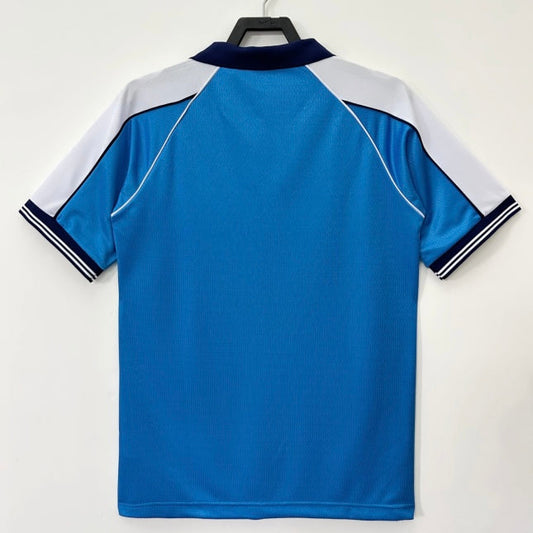 Blue Man City 99-01 home shirt with white and black accents on a hanger against a white background
