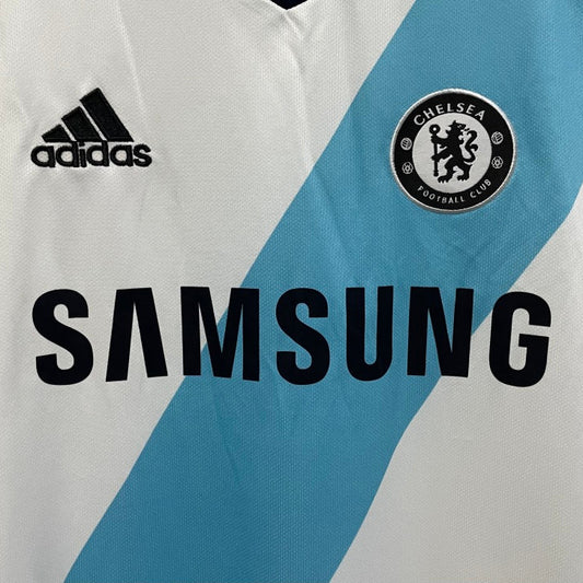 Close-up of a Chelsea 12/13 away shirt with Adidas and Samsung logos, featuring Chelsea FC emblem.