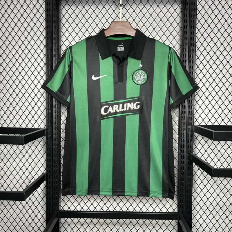 Green and black striped Celtic 06/07 jersey with Nike and Carling logos on a hanger against a grid background.