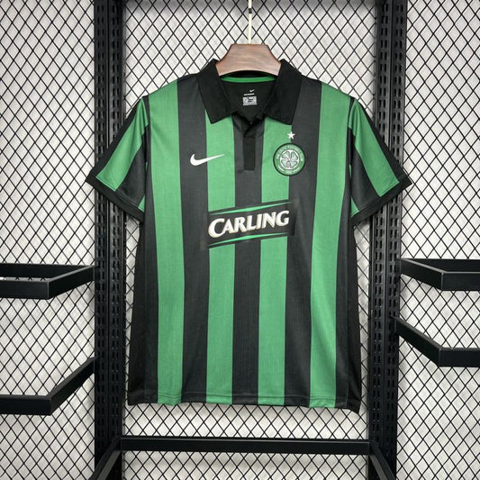 Green and black striped Celtic 06/07 jersey with Nike and Carling logos on a hanger against a grid background.