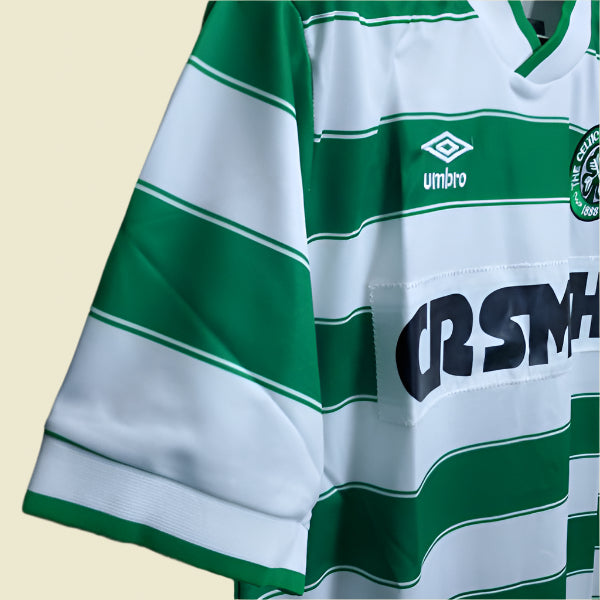 Green and white striped Celtic 85/86 home shirt with visible branding on a black background