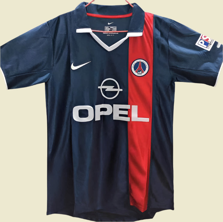 Blue 01/02 psg home shirt with red stripe and various logos on a plain background