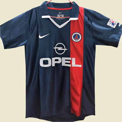 Blue 01/02 psg home shirt with red stripe and various logos on a plain background
