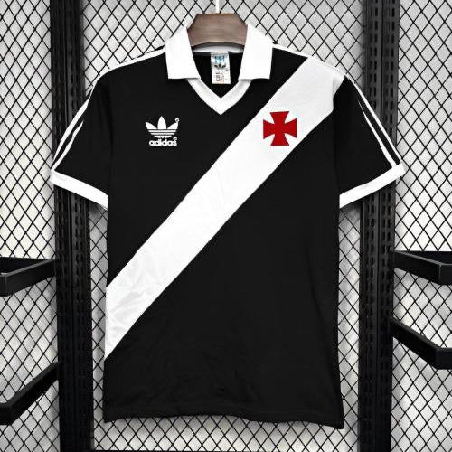 Black and white 1988 vasco de gama home shirt with a red cross logo on a hanger against a grid background