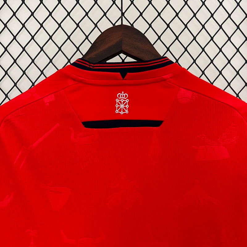 Red Osasuna 96/97 home shirt with a logo on a hanger against a chain-link fence background