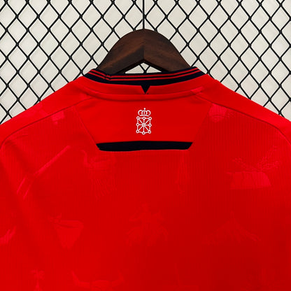 Red Osasuna 96/97 home shirt with a logo on a hanger against a chain-link fence background