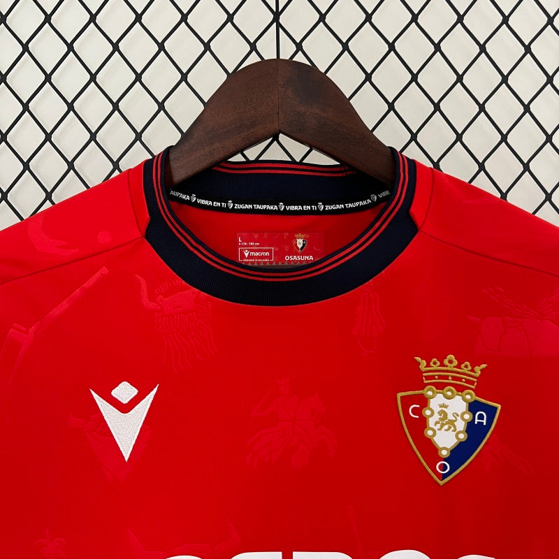 Red Osasuna 96/97 home shirt with a logo on a hanger against a chain-link fence background