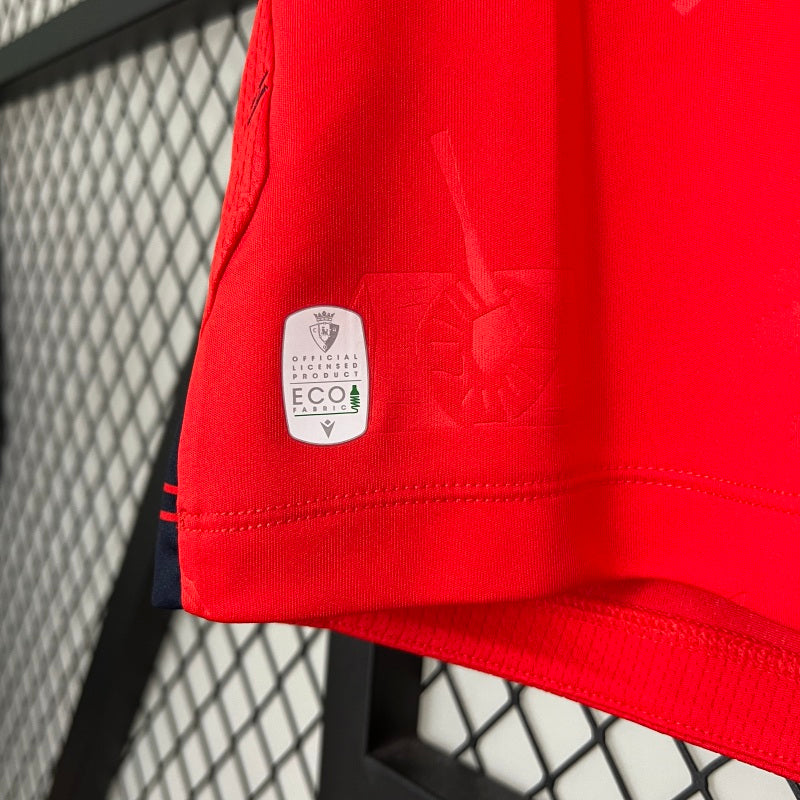 Red Osasuna 96/97 home shirt with a visible brand logo and 'Eco' label against a metal fence background