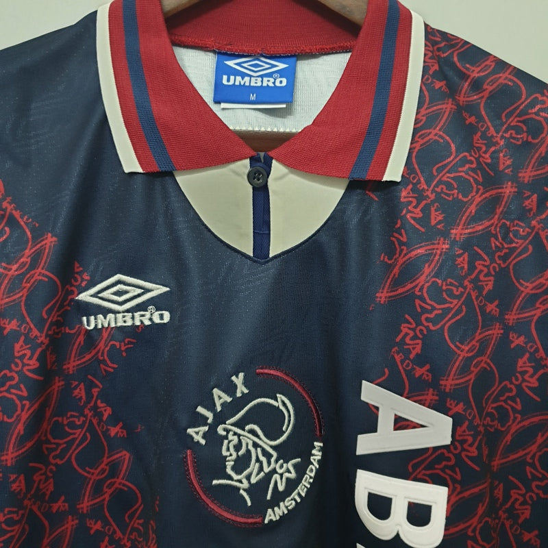 Navy Ajax 94/95 away shirt with red and white accents, featuring Umbro logo and 'Ajax Amsterdam' text.