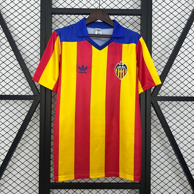 Red and yellow striped Valencia 80-82 away shirt with blue collar on a hanger against a black grid background