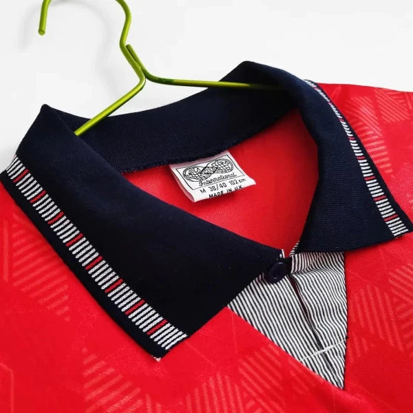 Red England 1990 away shirt with a navy collar and striped tie on a white background