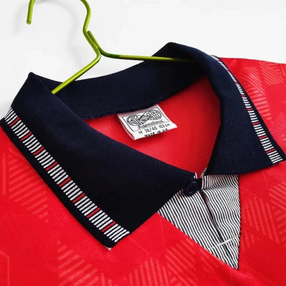 Red England 1990 away shirt with a navy collar and striped tie on a white background