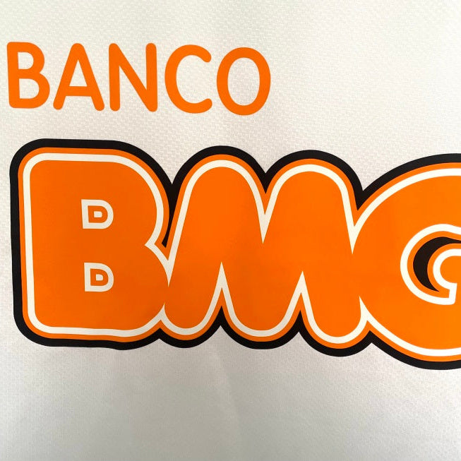 Logo of Banco BMG with orange text on a white Santos 11/12 long sleeve home shirt