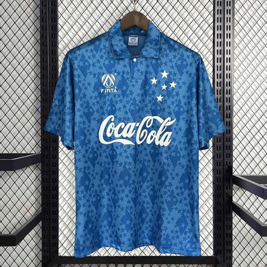 Blue 93-95 cruzeiro home shirt with Coca-Cola logo on a hanger against a grid background