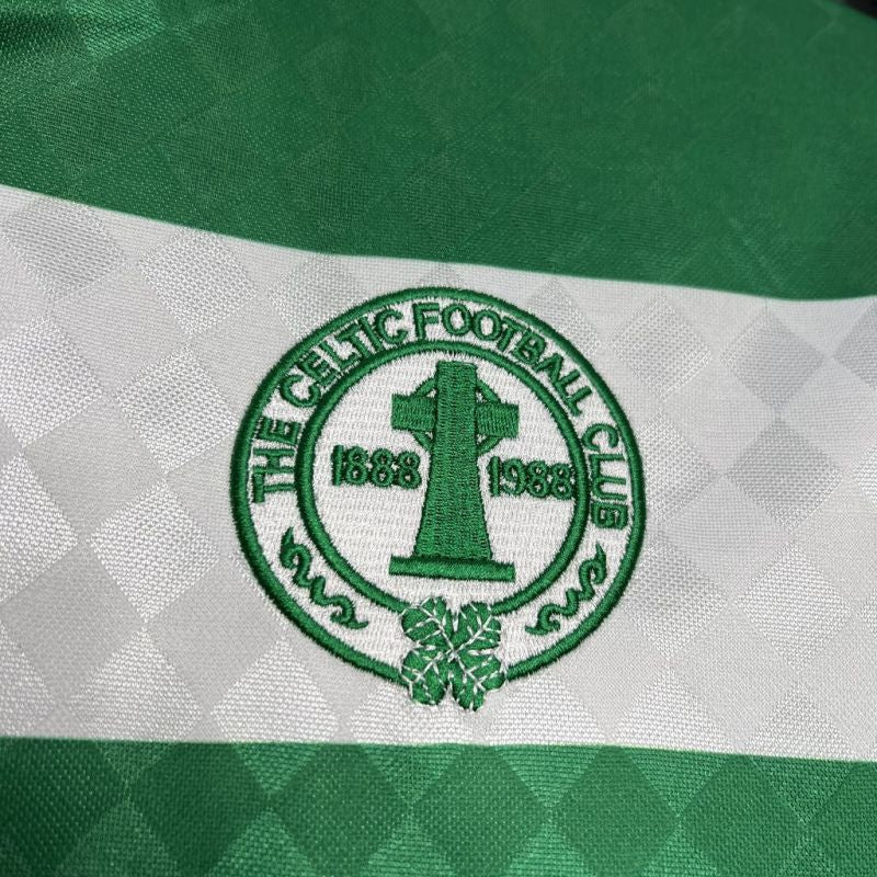 Close-up of The Celtic Football Club logo on a green and white striped Celtic 87/88 home shirt.