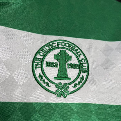 Close-up of The Celtic Football Club logo on a green and white striped Celtic 87/88 home shirt.