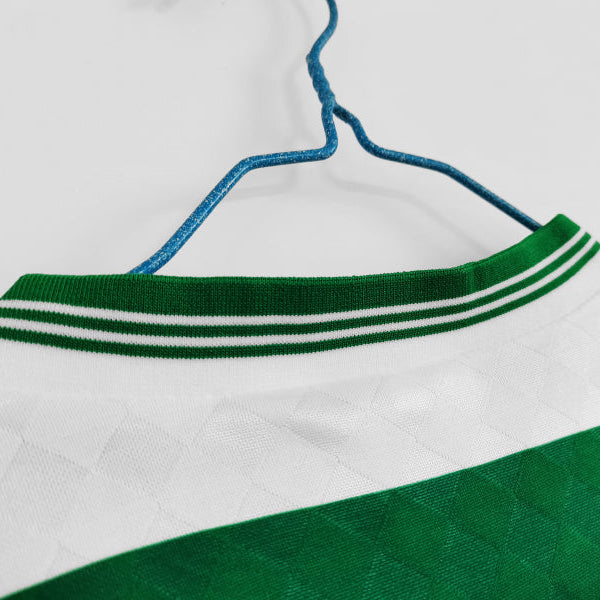 Close-up of a Celtic 87/88 long sleeve home shirt with green and white details on a hanger