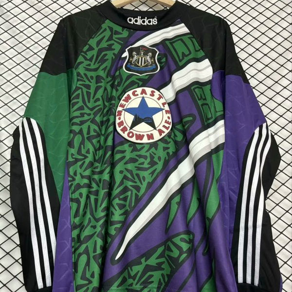 Colorful Newcastle 95/96 gk 2nd shirt with Adidas and Newcastle United logos on a checkered background