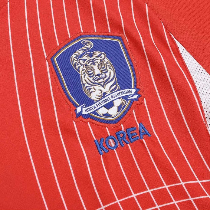 Red South Korea 2002 home shirt with a blue and white emblem featuring a tiger and the word 'Korea'.
