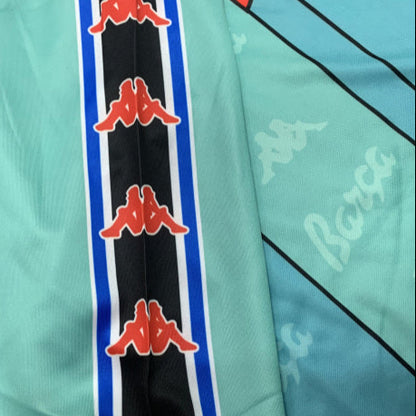 Teal Barcelona 96/97 away shirt with red and black Kappa logos on a gray surface