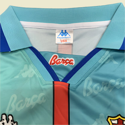 Teal Barcelona 96/97 away shirt with red and blue accents, featuring 'Barca' branding, on a textured gray background.