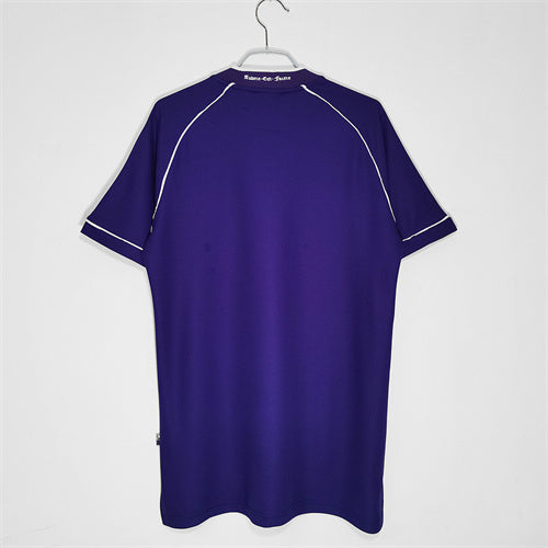Purple Tottenham 98/99 away shirt with white accents on a hanger against a white background