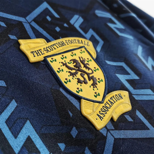 Close-up of a Scottish Football Association logo on a Scotland 1992 home shirt with a blue and black pattern.