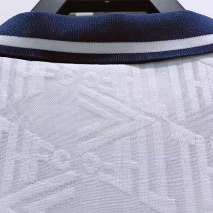 Close-up of a Tottenham 91-93 home shirt with a blue collar and white patterned design.