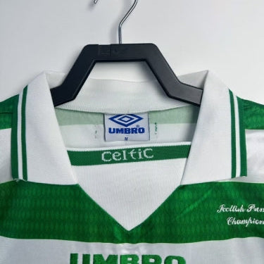 Green and white Celtic 98/99 premiership champions home shirt with Umbro logo on a hanger against a white background